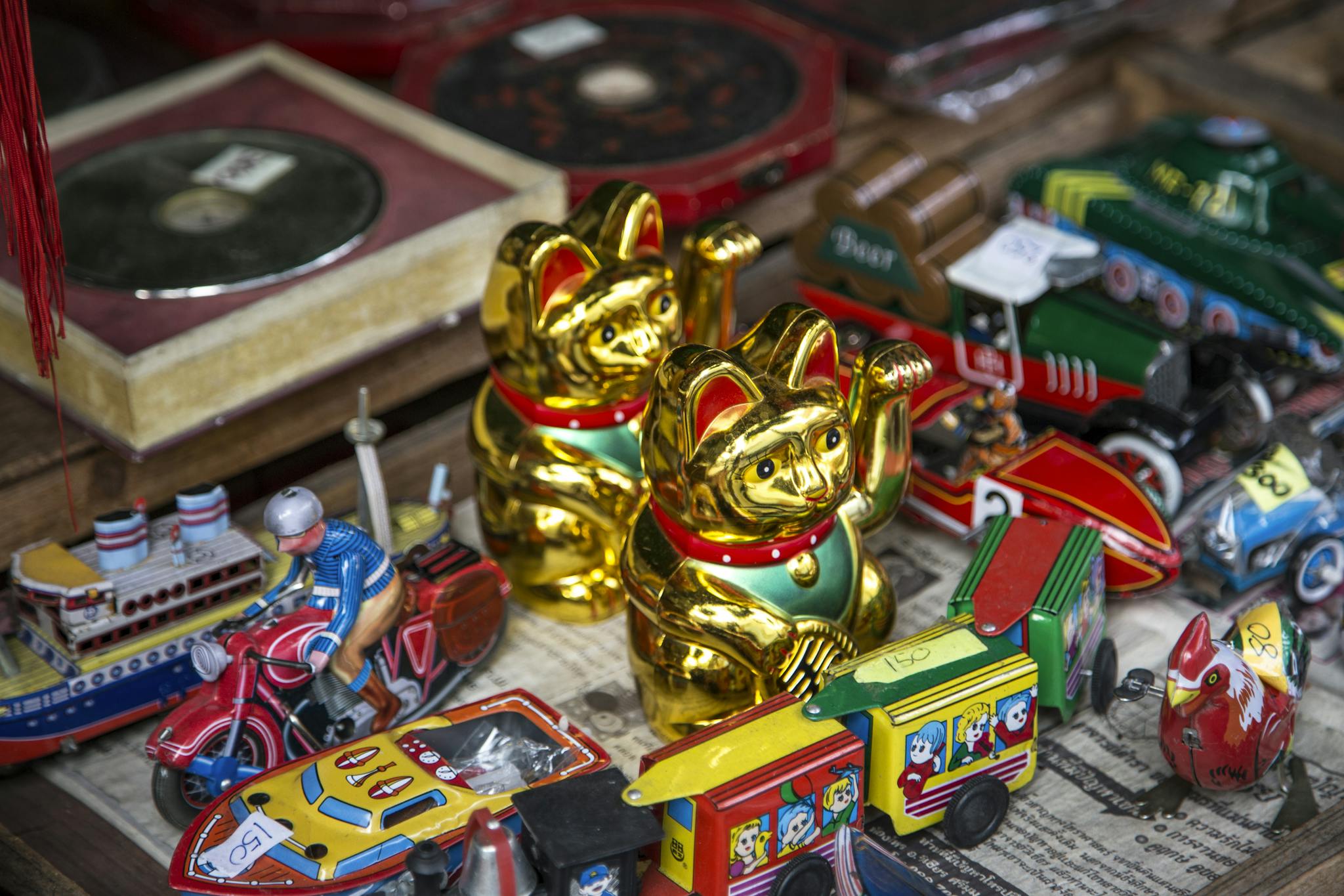 A vibrant display of vintage toys, featuring Maneki-neko figurines and tin vehicles, creating a retro feel.