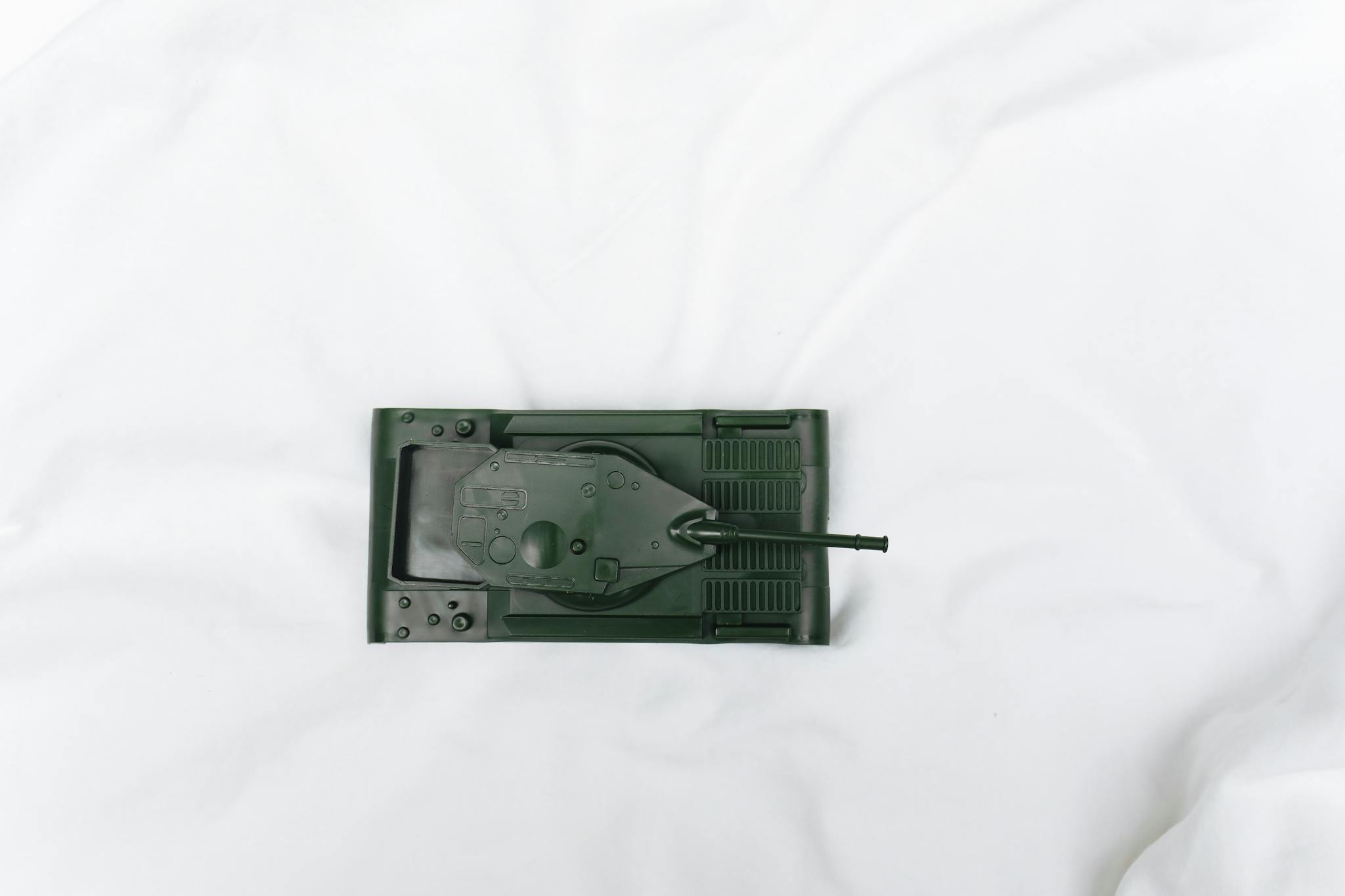 Green toy tank viewed from above on a white surface, emphasizing playtime and imagination.